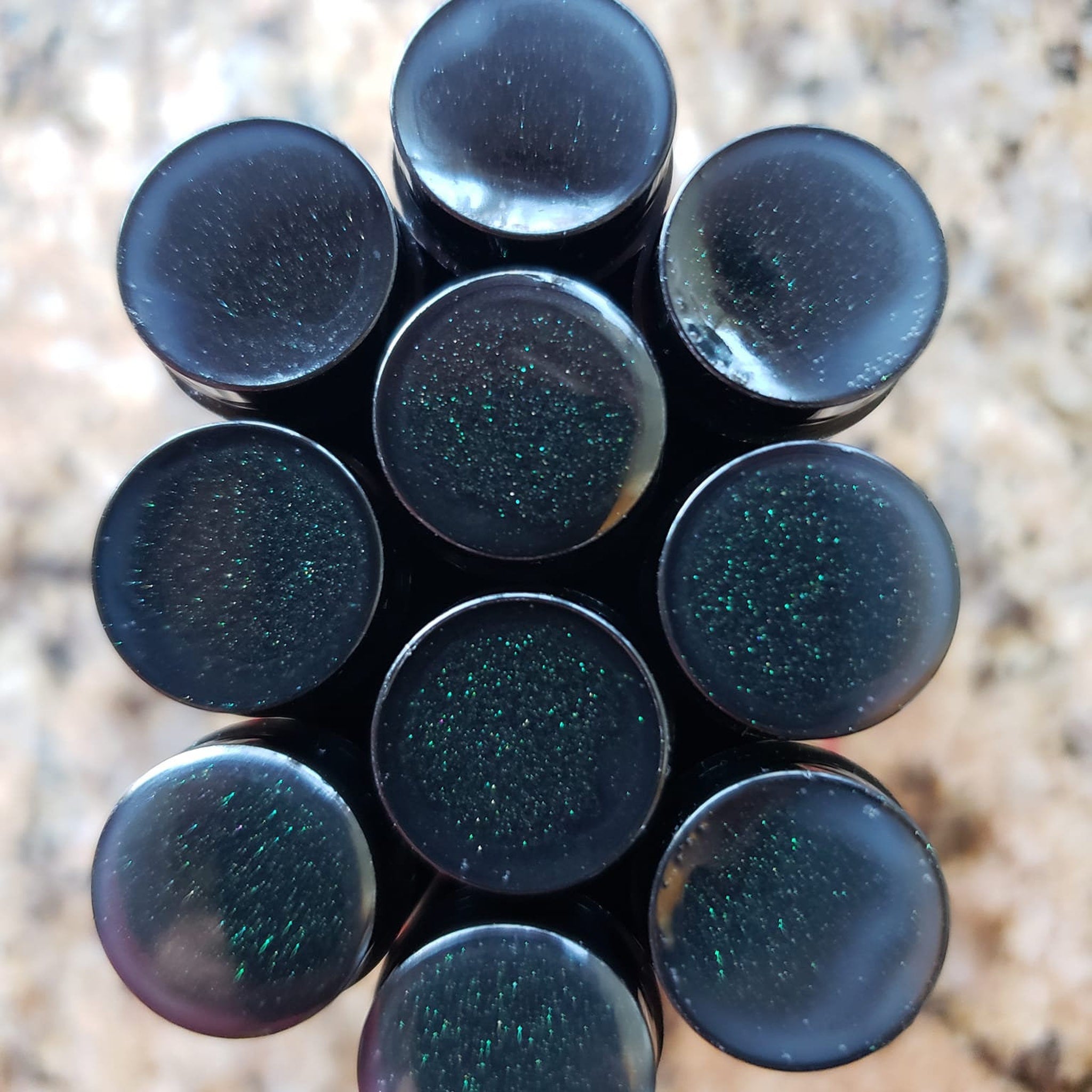 Black plugs with green glitter, glossy finish, stacked together