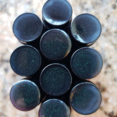 Black plugs with green glitter, glossy finish, stacked together