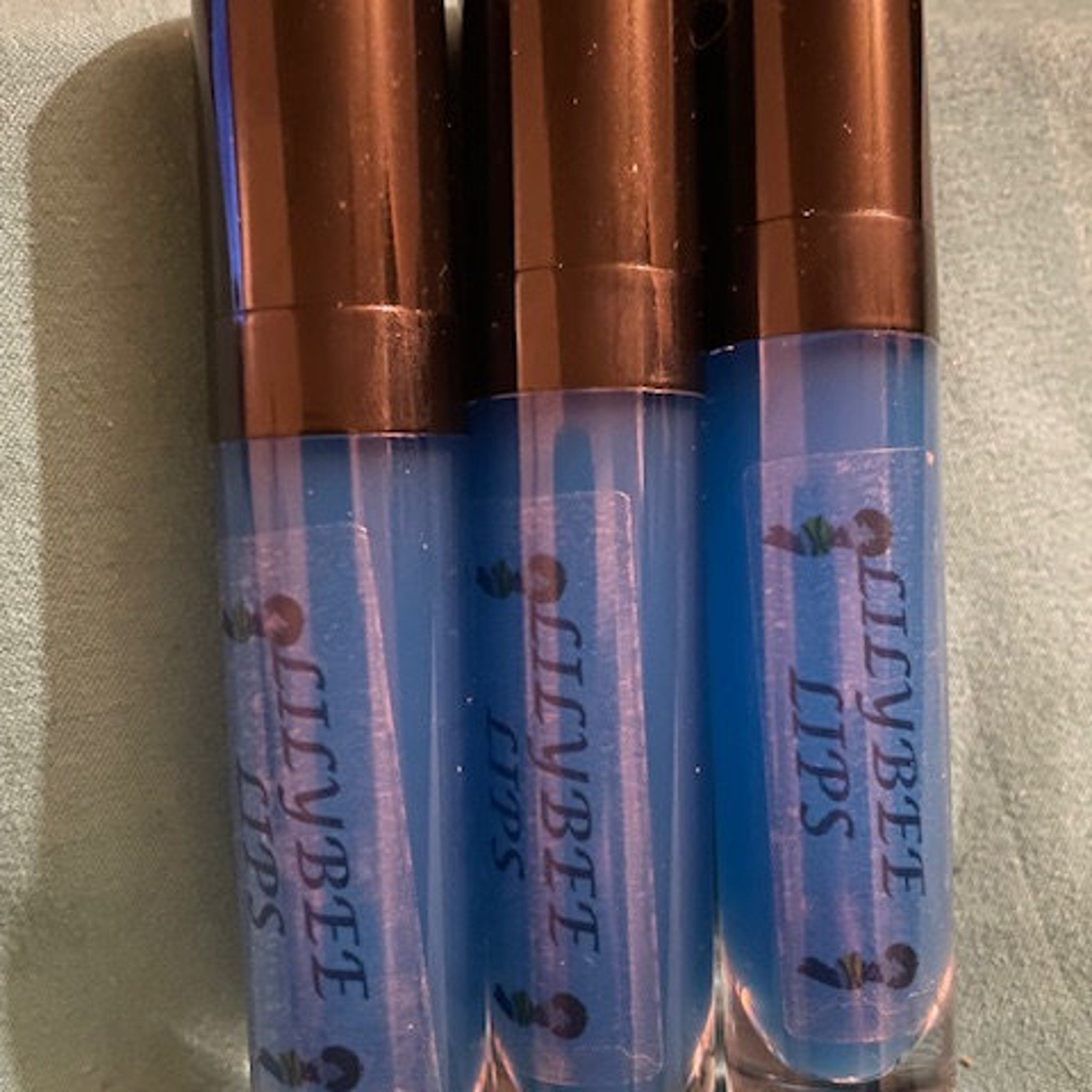 Lip gloss tubes with blue liquid, brown cap, and Lilybee Lips text on label