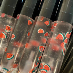 Lip gloss tubes with watermelon pattern, clear liquid, and black caps