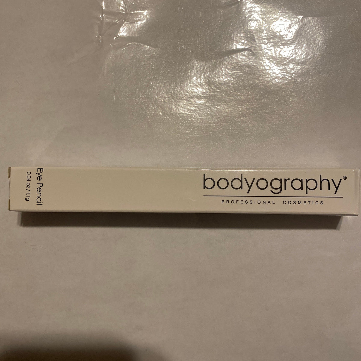 Close-up of Bodyography Black Walnut Eye Pencil showing rich brown shade and sleek wooden-textured packaging