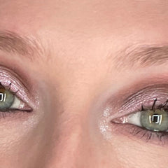Eyeshadow with pink shimmer, light color, and applied to eyelids for makeup look