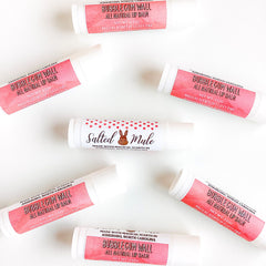 Lip balm tubes with pink labels and white tubes, "Bubblegum Wall" text visible