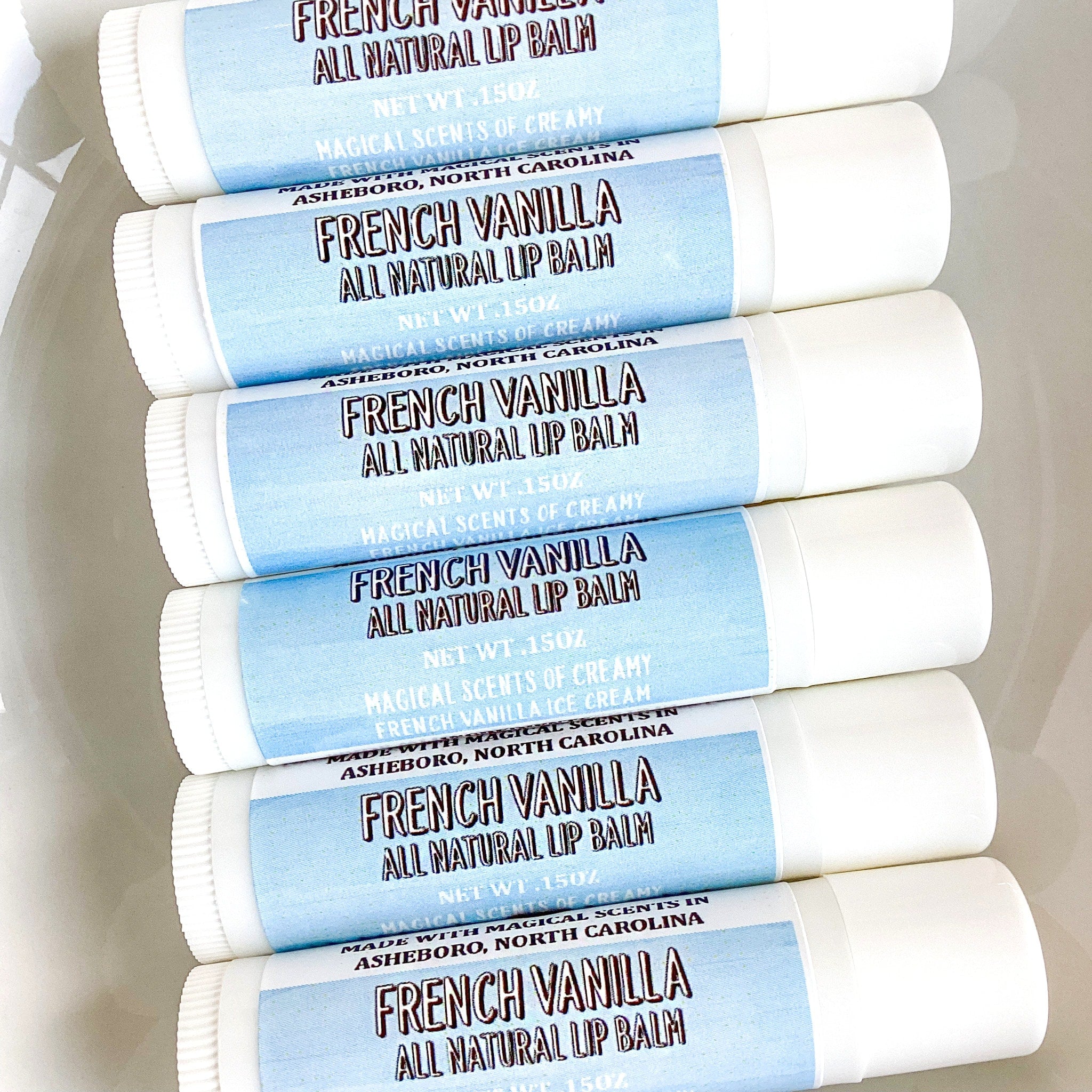 Lip balm tubes with white and light blue labels, French Vanilla text visible.