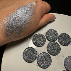 Close-up of dark gray holographic glitter eyeshadow in 26mm pan with shimmering magnesium particles