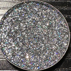 Close-up of dark gray holographic glitter eyeshadow in a round 26mm metal pan with reflective sparkles