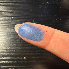 Close-up of dark blue duochrome pressed glitter eyeshadow pan with shimmering lagoon effect