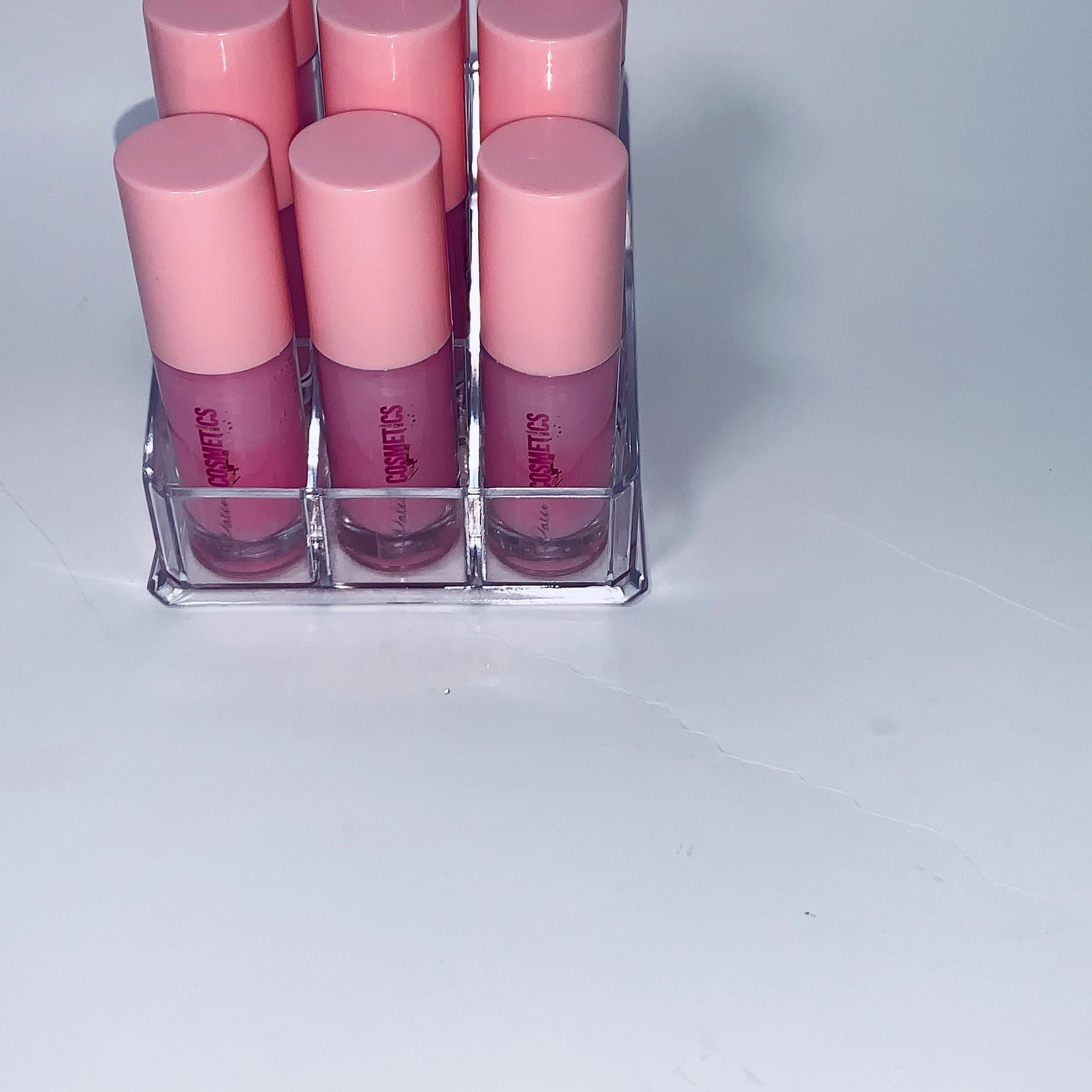 Lip gloss tubes with pink caps and clear holder, "Latee Cosmetics" text visible