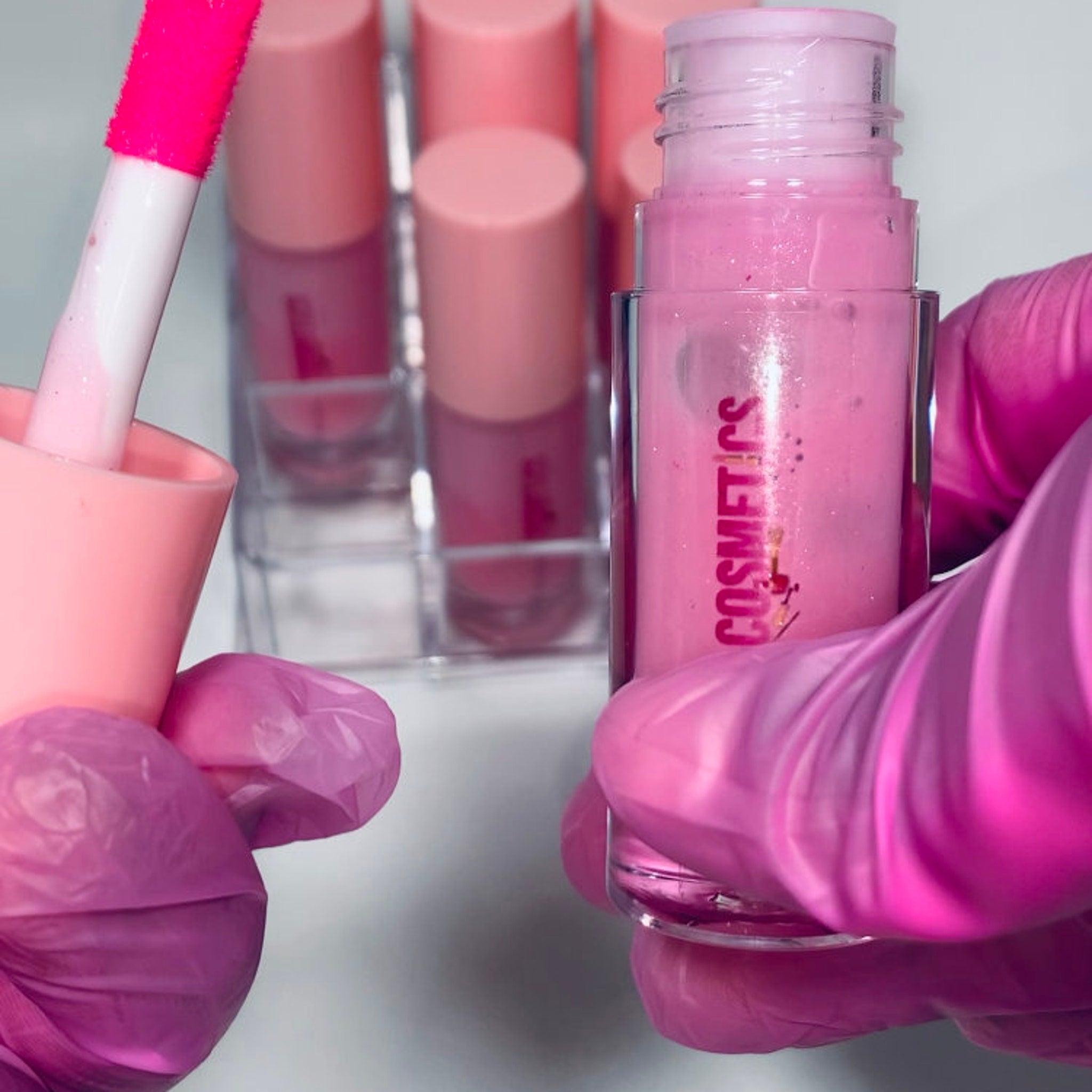 Lip gloss tubes with pink liquid, pink applicator, and pink "COSMETICS" text