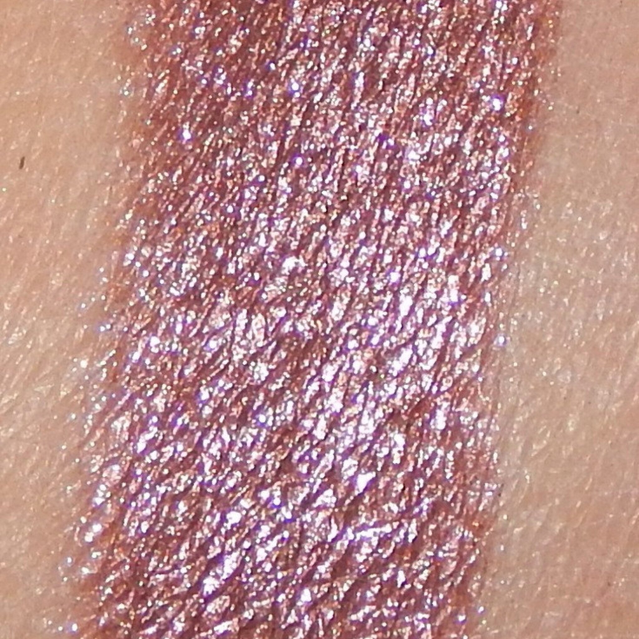 Close-up of shimmery pink mineral eyeshadow with gold flecks in sleek black compact