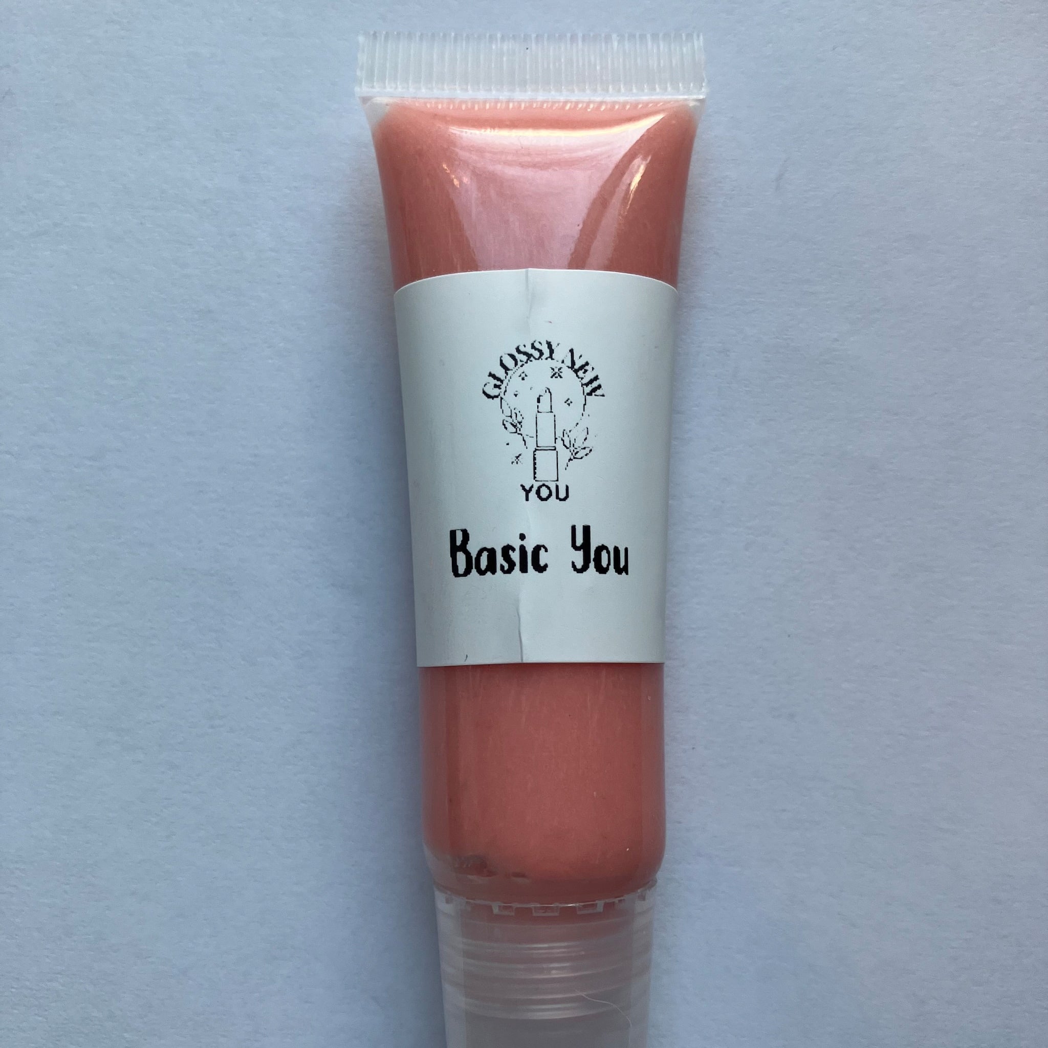 Lip gloss tube with peach color, clear plastic, and Glossy New You label