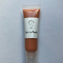 Lip gloss tube with peach color, clear plastic, and "Life's a Beach" text from Glossy New You