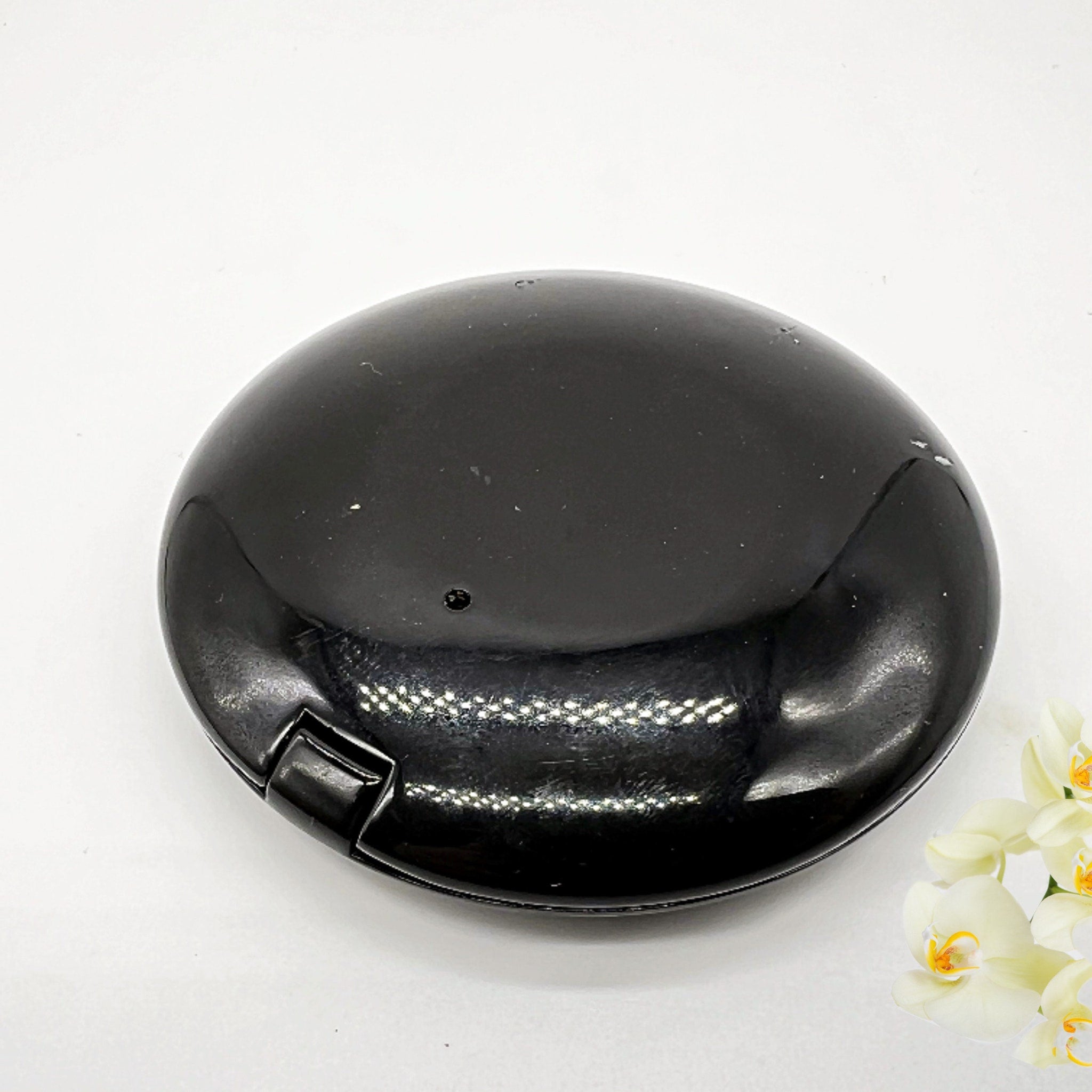 Black compact case with glossy finish and rounded shape on white background