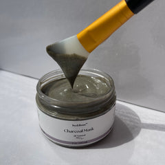 Charcoal face mask jar with gray mask and yellow applicator being used