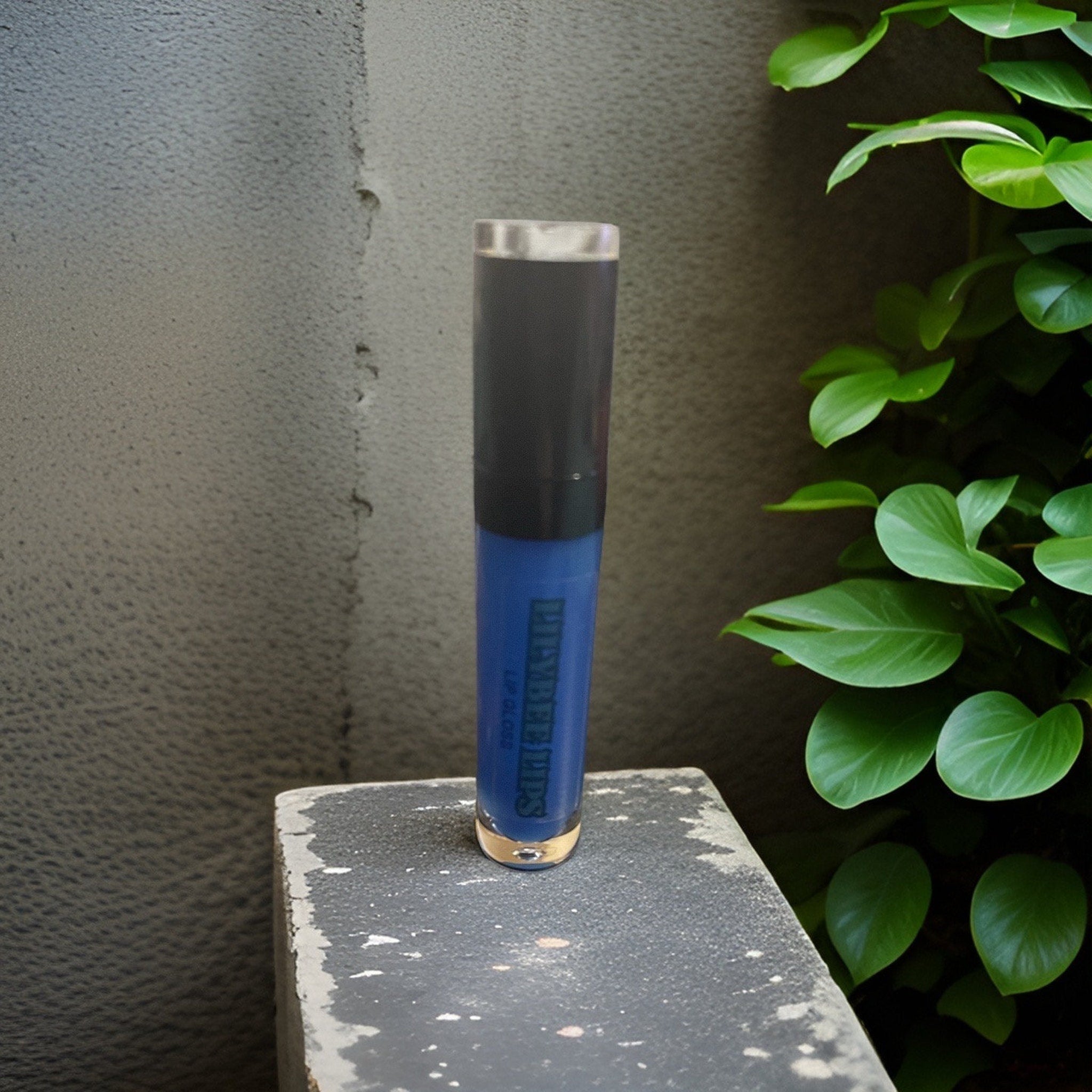 Lip gloss tube with blue, black, and gold details, PLAYBEE IPS text visible