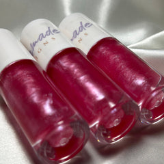 Lip gloss tubes with pink liquid, clear glass, and white lids with "made" text