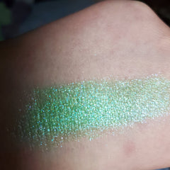 Close-up of Attack Eye Shadow pan showing vibrant pigmented powder with shimmer finish in a sleek black compact