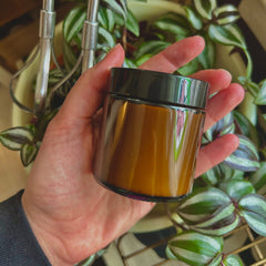 Close-up of rich golden Wagyu tallow body butter in a sleek black jar with gold accents, showcasing its creamy texture