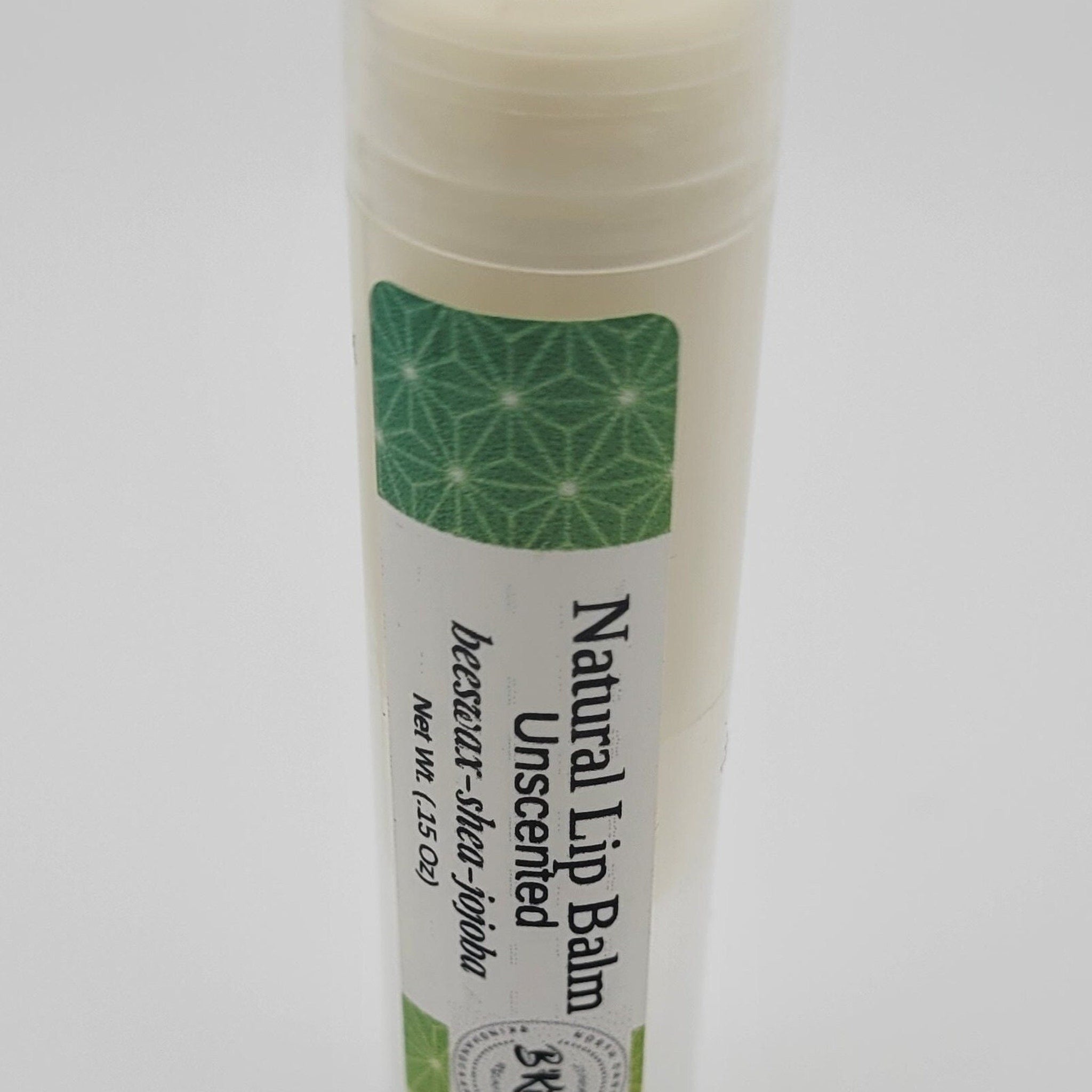 Lip balm tube with green geometric pattern label and white tube, "Natural Lip Balm" text visible