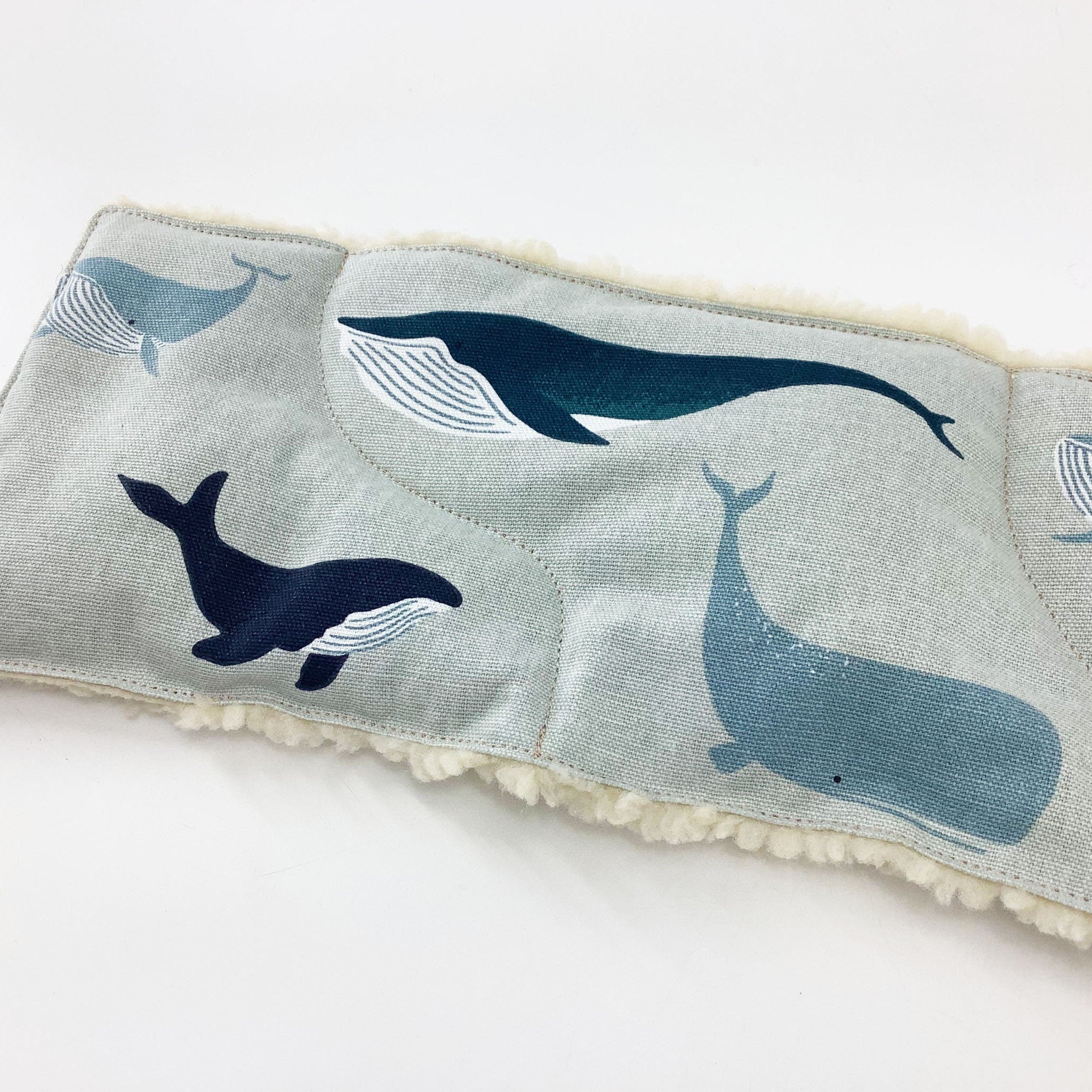 Whale print fabric with blue whales on light blue fabric with white fluffy trim