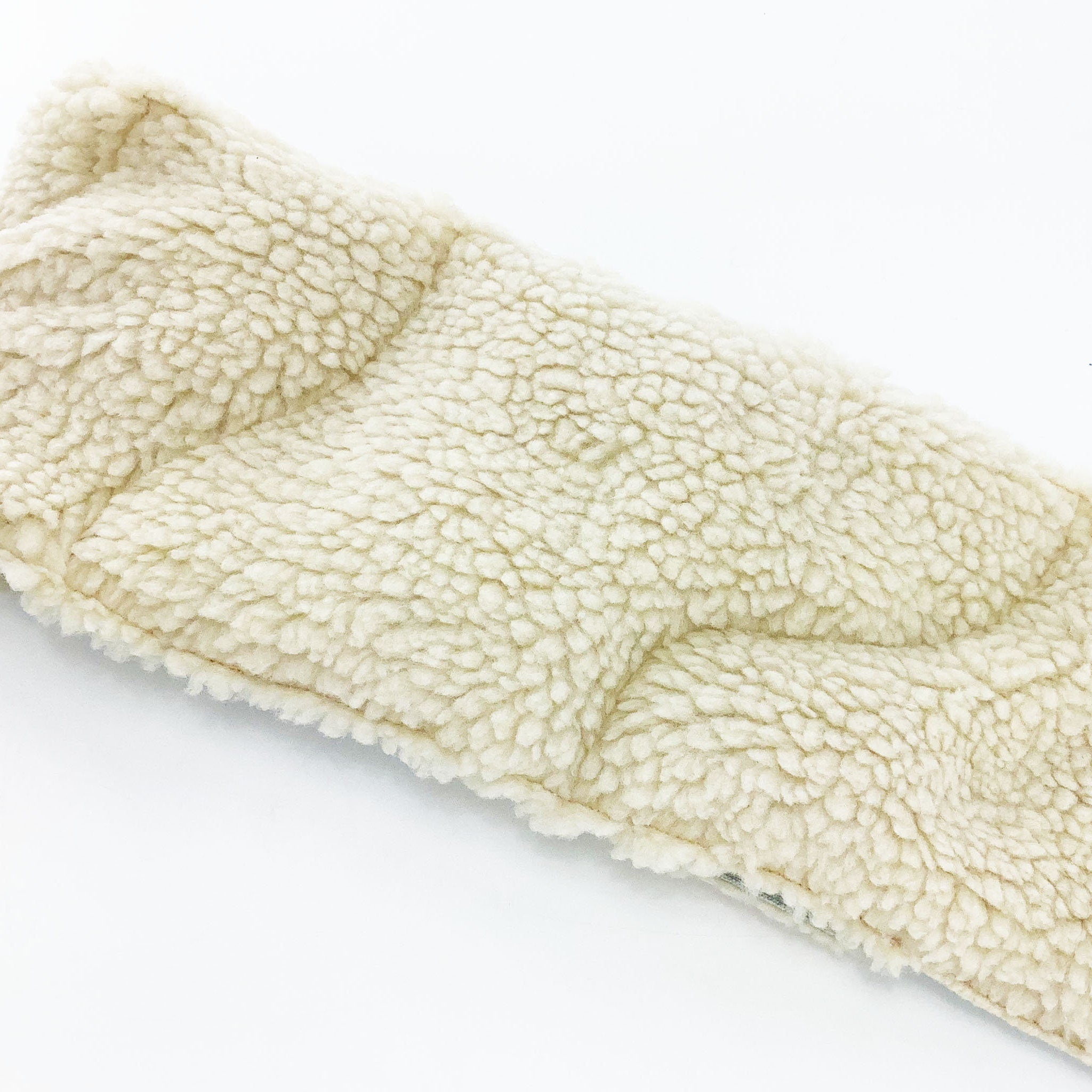Cream-colored plush material with quilted pattern and visible stitching on white background