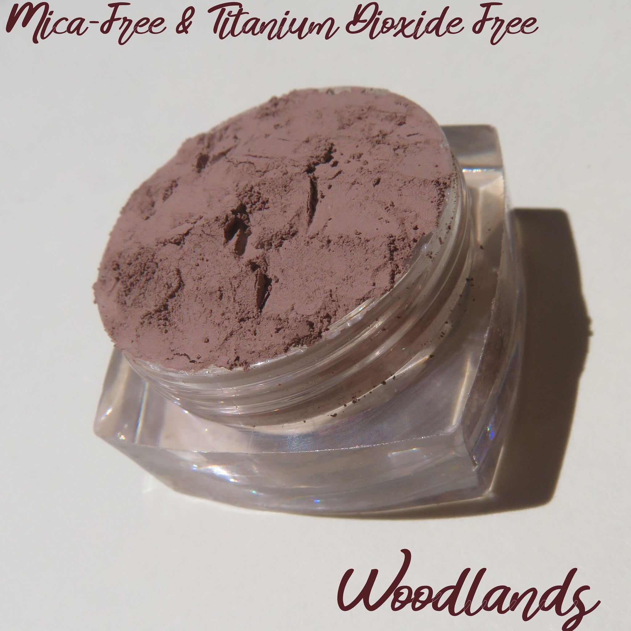 Close-up of loose matte brown mineral eyeshadow powder with eco-friendly packaging, showcasing fine texture and rich pigment.
