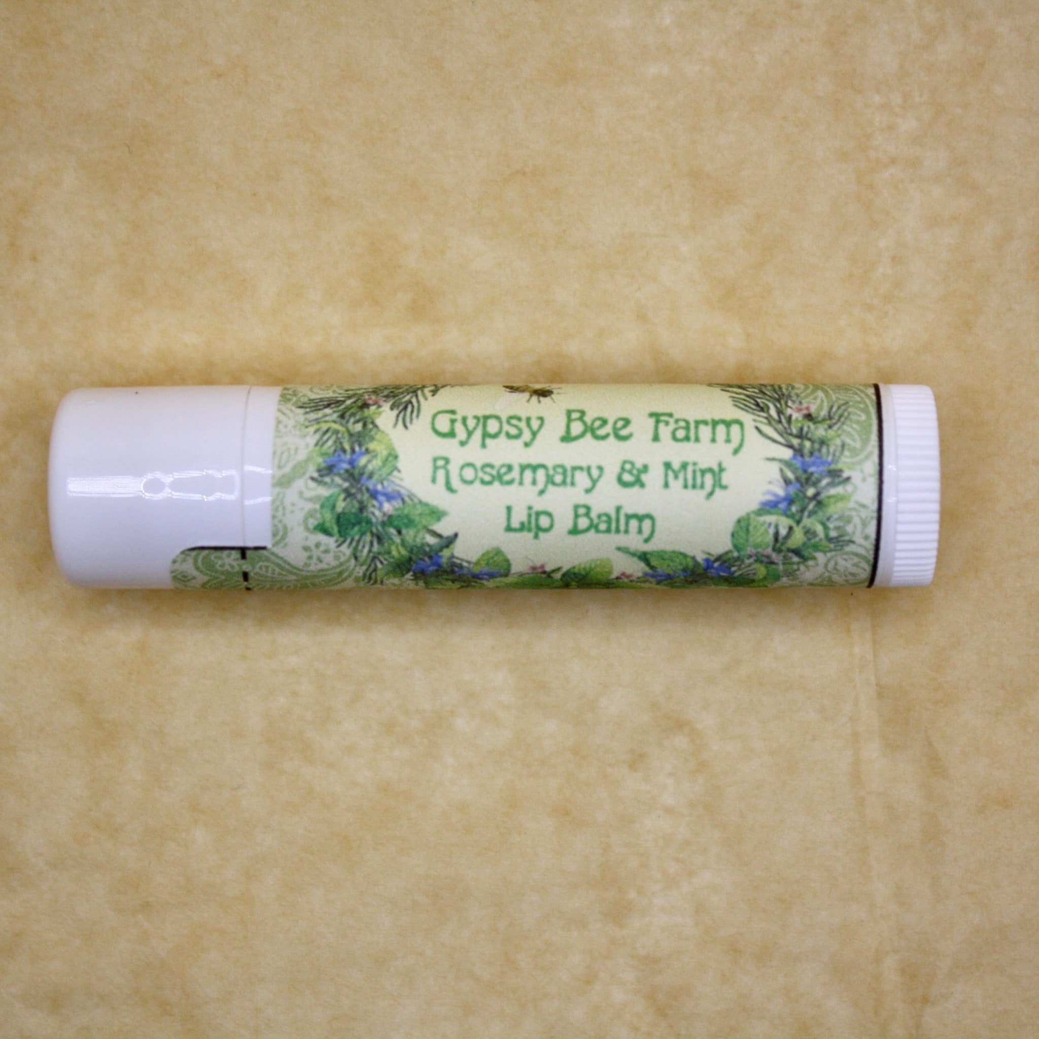 Lip balm tube with white and green label, floral pattern, "Gypsy Bee Farm" text