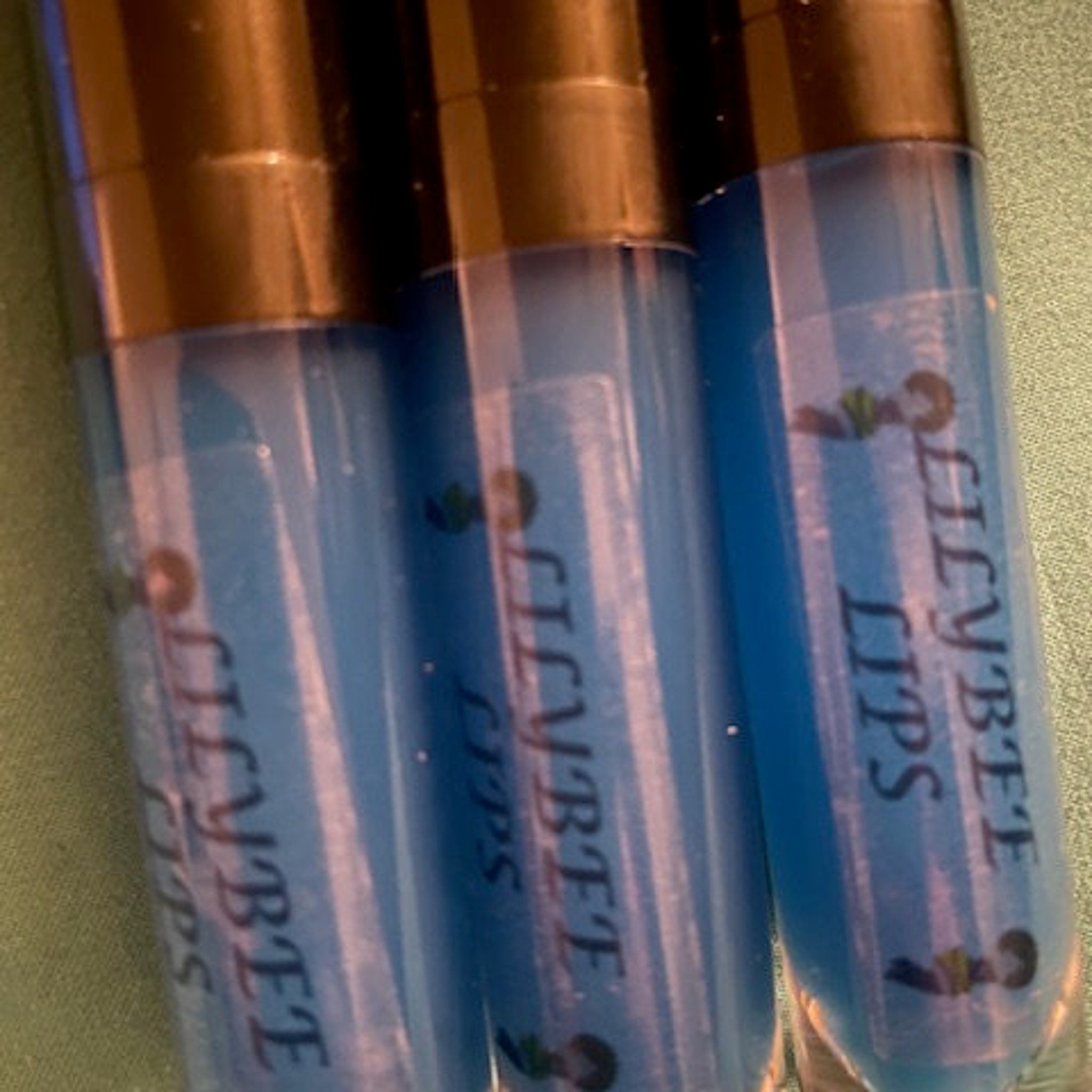 Lip gloss tubes, blue liquid, black caps, "Ellybte Lips" text, clear plastic tubes