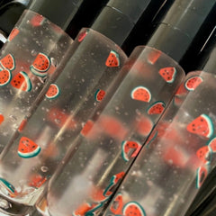 Lip gloss tubes with watermelon slice pattern, clear liquid, and black caps