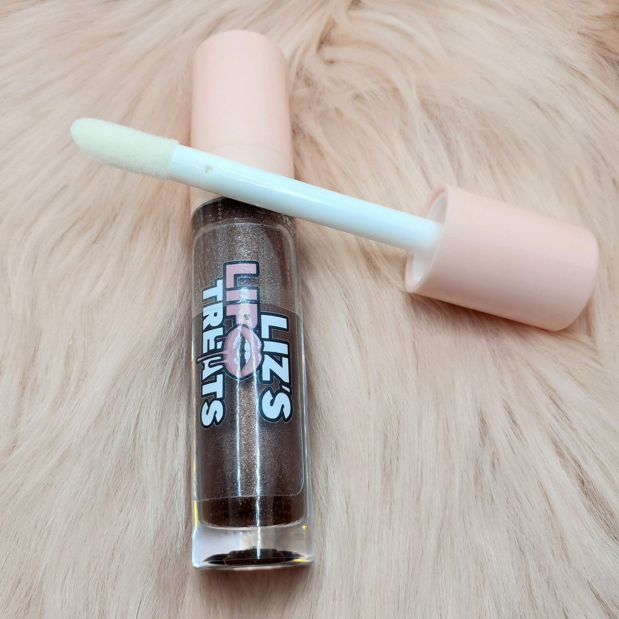 Lip gloss tube with brown glitter, pink cap, and applicator, Liz's Treats brand visible