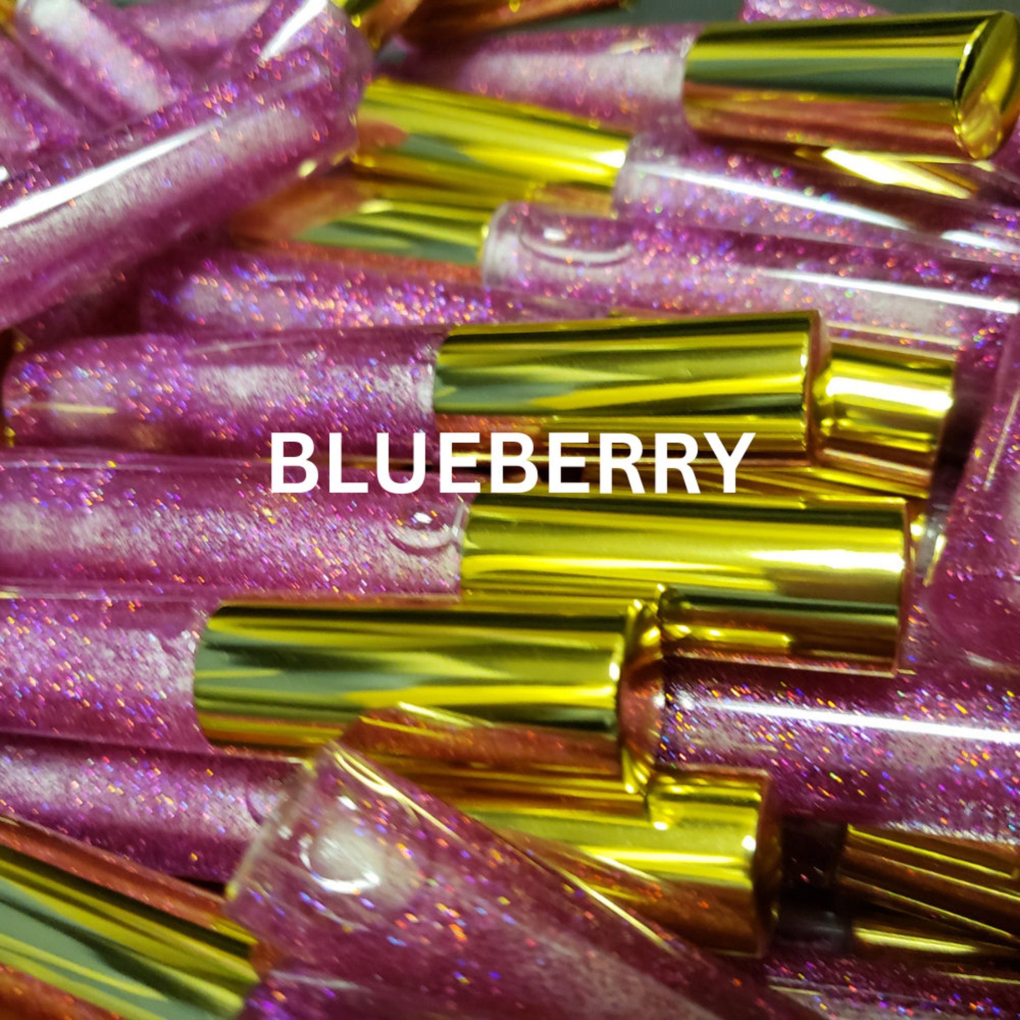 Lip gloss tubes with pink glitter and gold caps, "BLUEBERRY" text visible