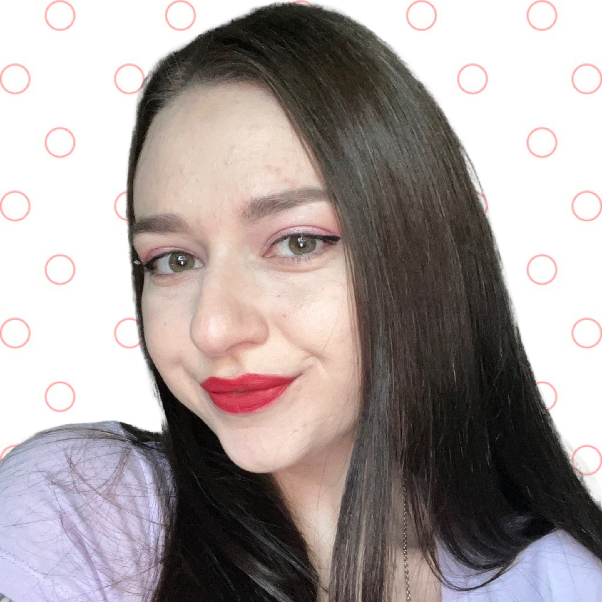 Woman with dark hair, red lipstick, and pink eye makeup smiling at the camera.