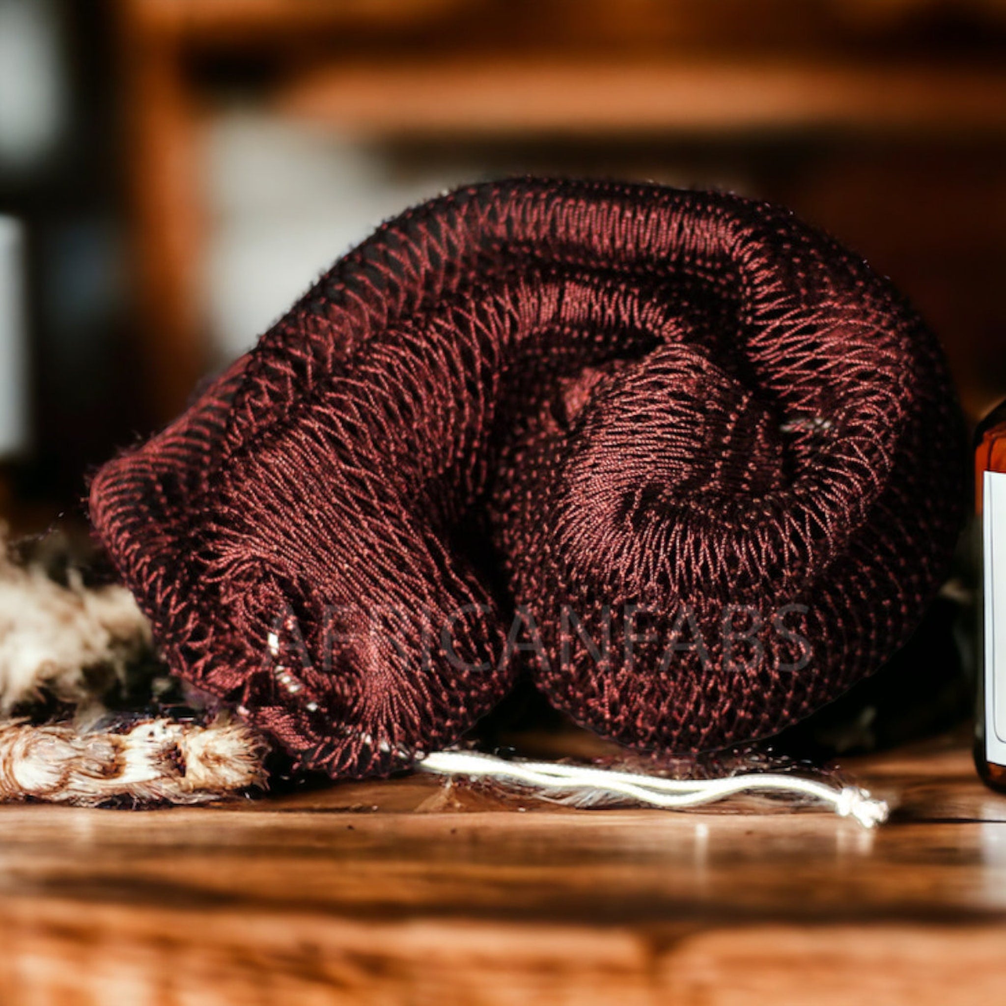 Textured African exfoliating net sponge draped elegantly over bamboo tray, showcasing its woven lattice design for skin renewal