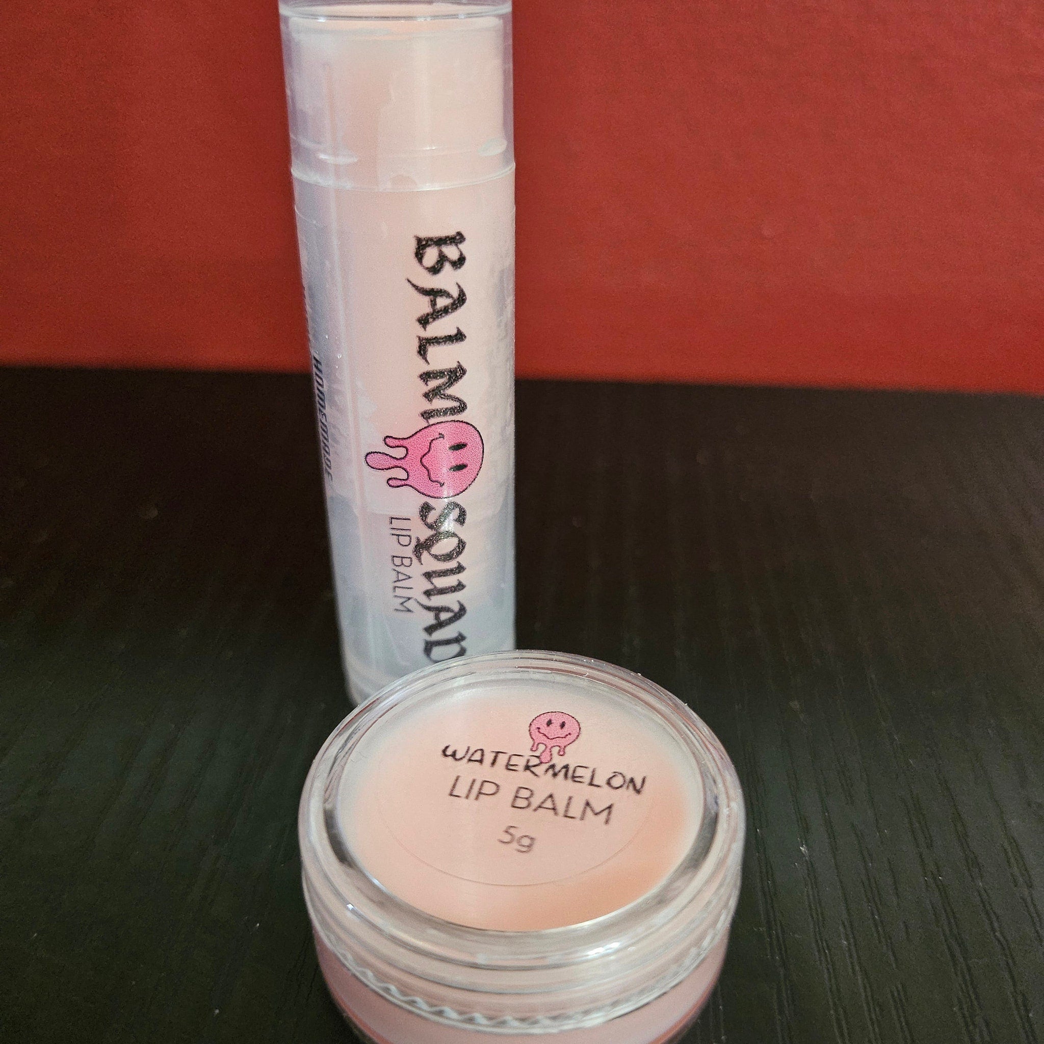 Lip balm tubes and jar with pink balm, clear plastic, and black text "Balm Squad" and "Watermelon Lip Balm