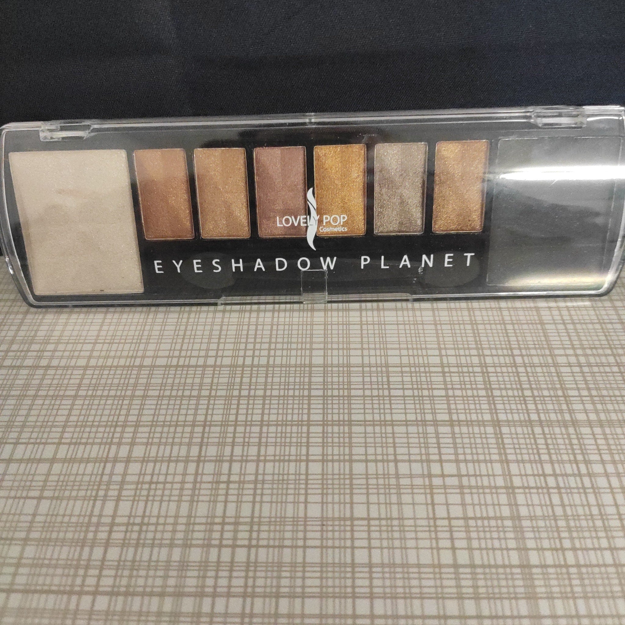 Black eyeliner pencil displayed diagonally on sleek silver makeup palette with mirror