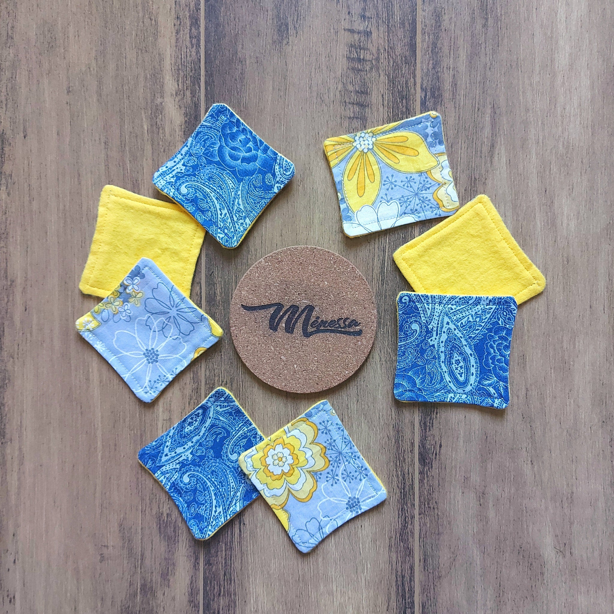 Coasters with blue paisley and yellow floral patterns, plus cork Meressa coaster on wood surface
