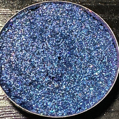 Close-up of dark blue duochrome pressed glitter eyeshadow pan with shimmering lagoon effect