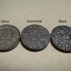 Side view of black holo pressed glitter eyeshadow in 26mm pan showcasing reflective particles