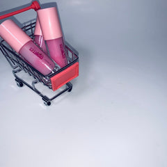 Lip gloss tubes with pink lids and clear tubes in a miniature shopping cart, "Lattia Cosmetics" visible