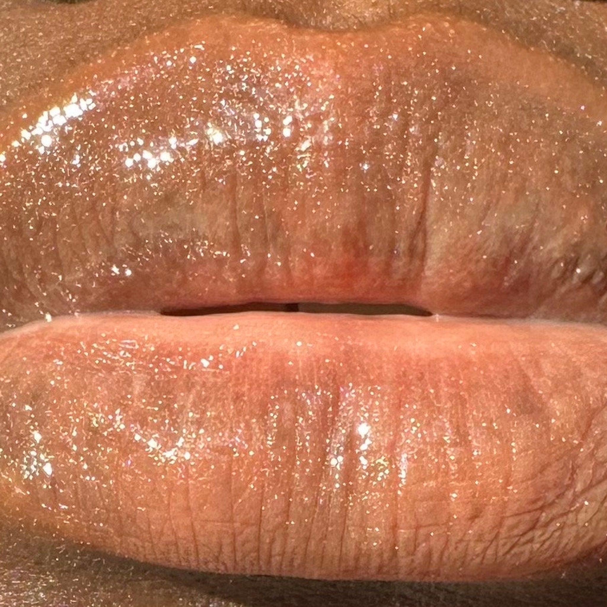 Lip gloss with shimmering glitter, light peach color, and glossy finish on lips