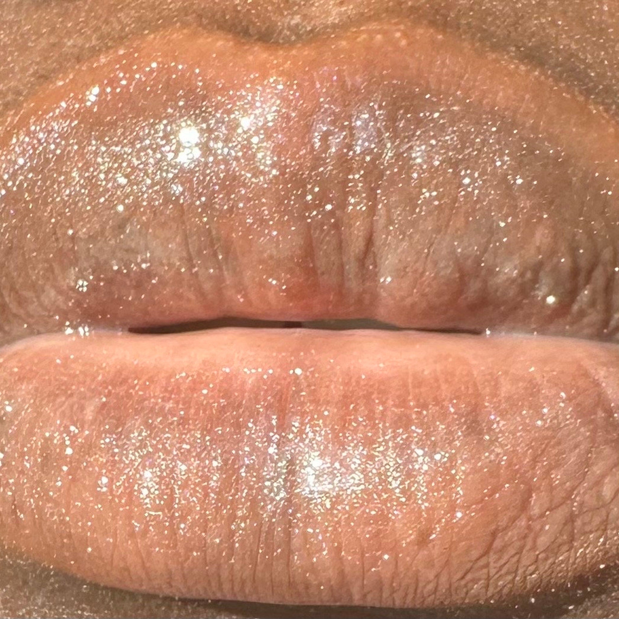 Lip gloss with shimmering glitter, light pink color, and glossy finish