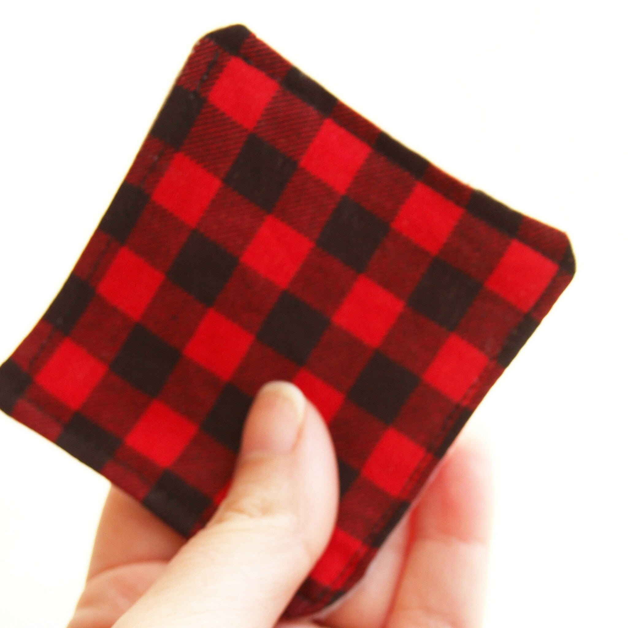 Red and black plaid square fabric held in hand, close up view