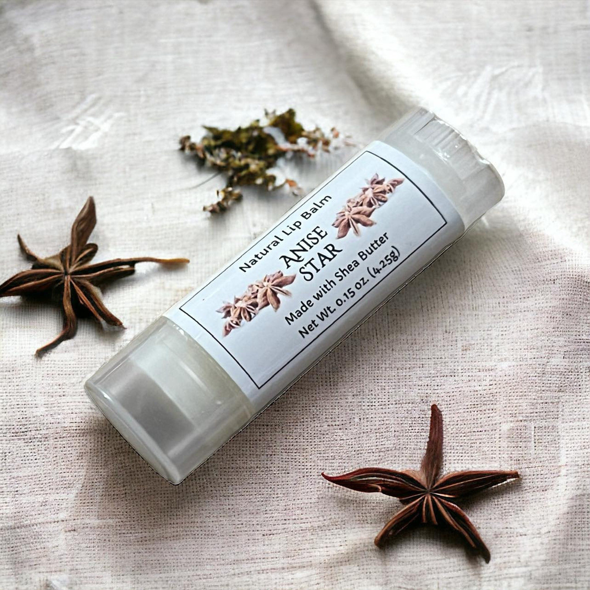 Lip balm tube with white label, clear tube, and star anise on linen cloth