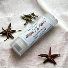 Lip balm tube with white label, clear tube, and star anise on linen cloth