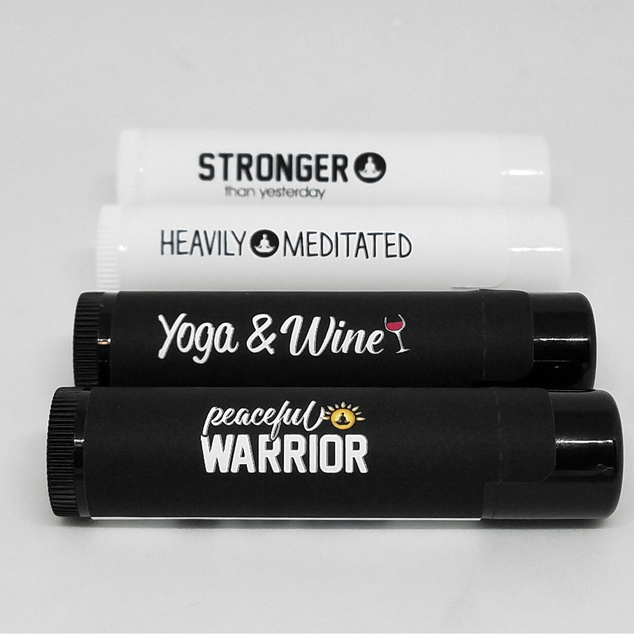 Lip balms, white and black tubes, with text "Yoga & Wine" and "peaceful WARRIOR