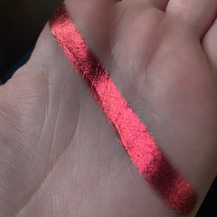 Single multichrome Rubrum eye shadow pan with shifting red-copper-gold hues in compact round case