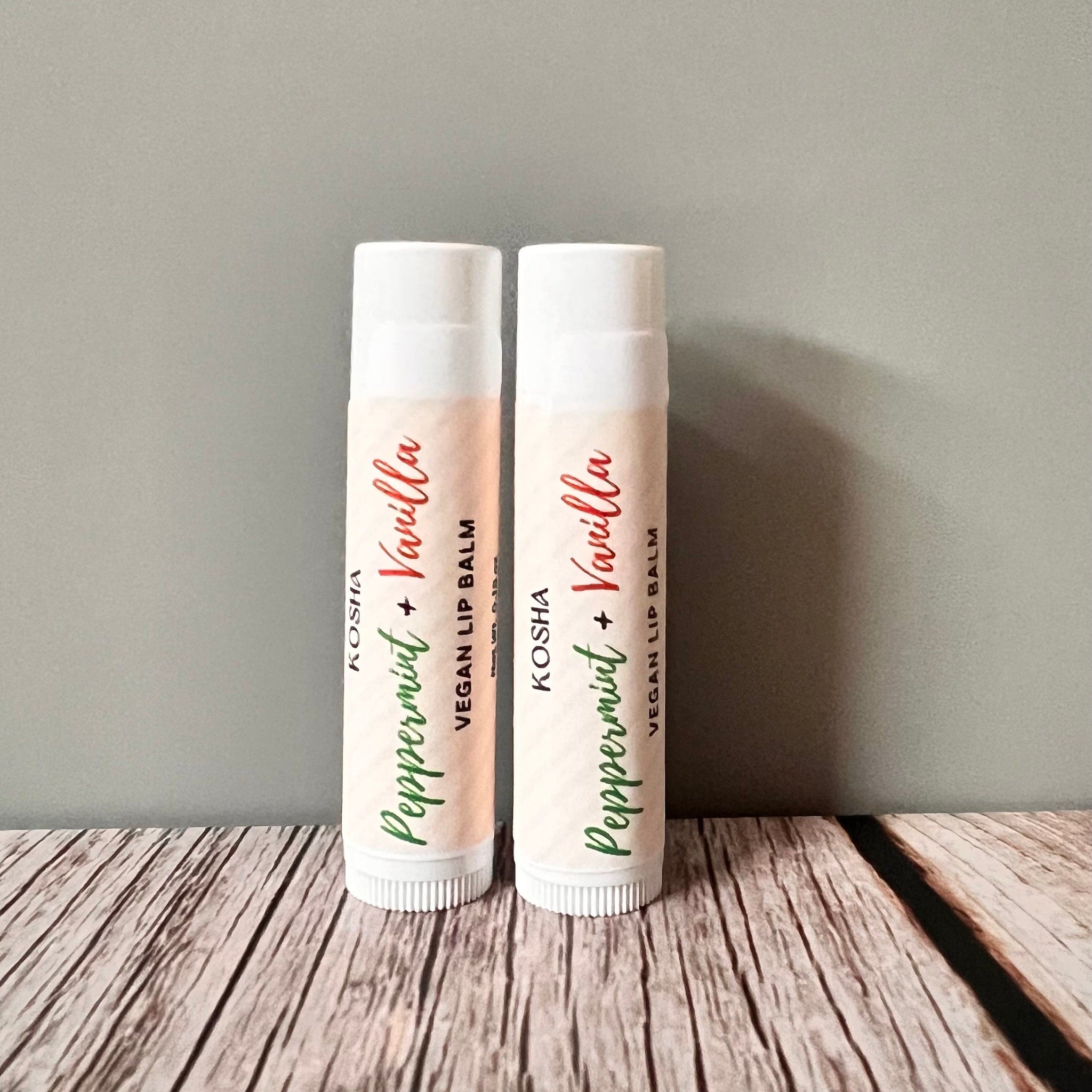 Lip balm tubes with white and peach labels, green and red text, and KOSHA brand name displayed