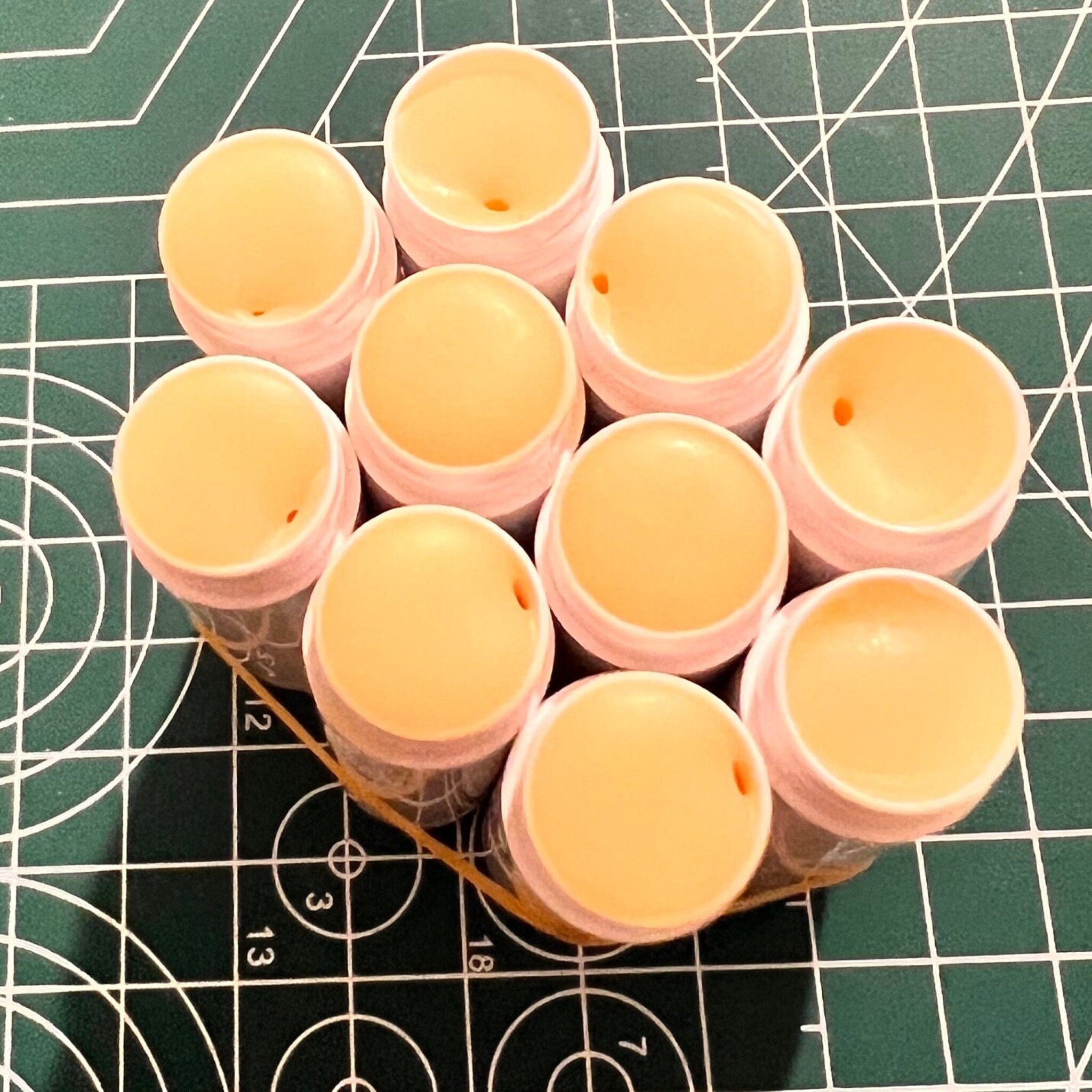 Lip balm tubes with pink rims and yellow balm, grouped together with rubber band