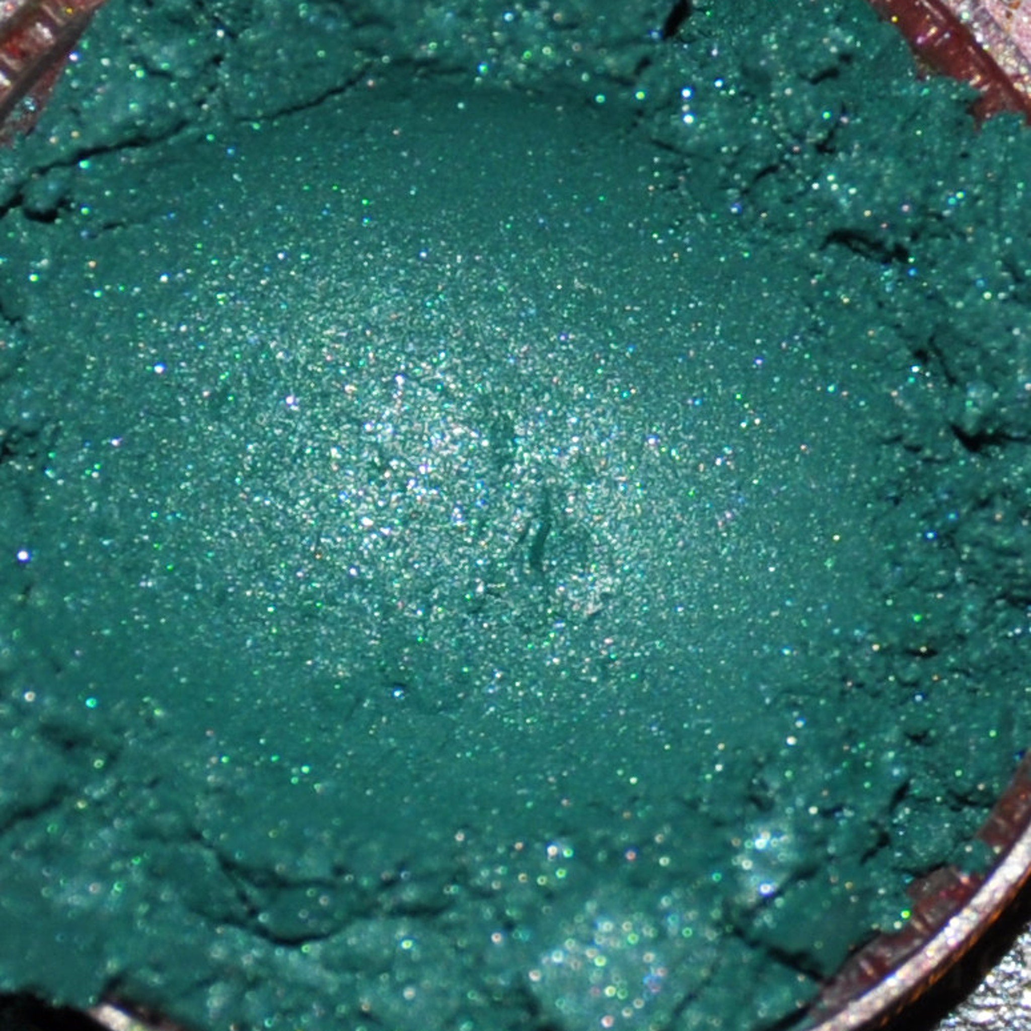 Close-up of mineral eye shadow powder in a sifter jar showing rich pigmentation and fine texture
