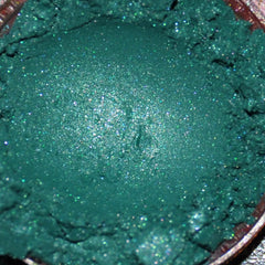 Close-up of mineral eye shadow powder in a sifter jar showing rich pigmentation and fine texture